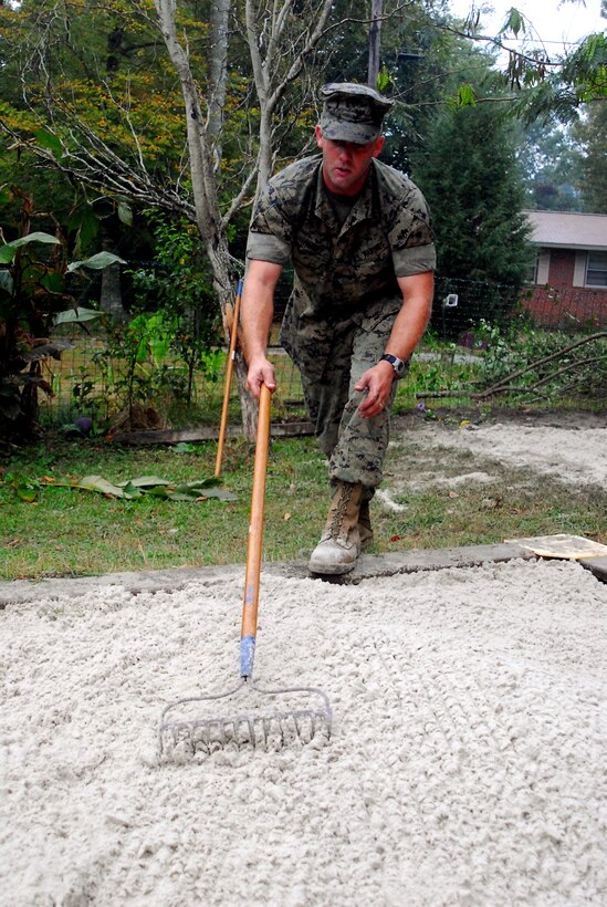 JACKSONVILLE, N.C. - Cpl. Nicholas Nunez, a telephone installer with Base Telephone, Headquarters and Support Battalion, Marine Corps Base, spreads out freshly dumped sand over a sandbox at the Montessori Children's School here Oct. 17. Nunez was among 21 Marines with the battalion who volunteered to help the school with their Project Green Space, which is an effort to make their outdoor area a place where children can learn to play, grow and socialize. (Official U.S. Marine Corps photo by Cpl. Brandon R. Holgersen)(released)