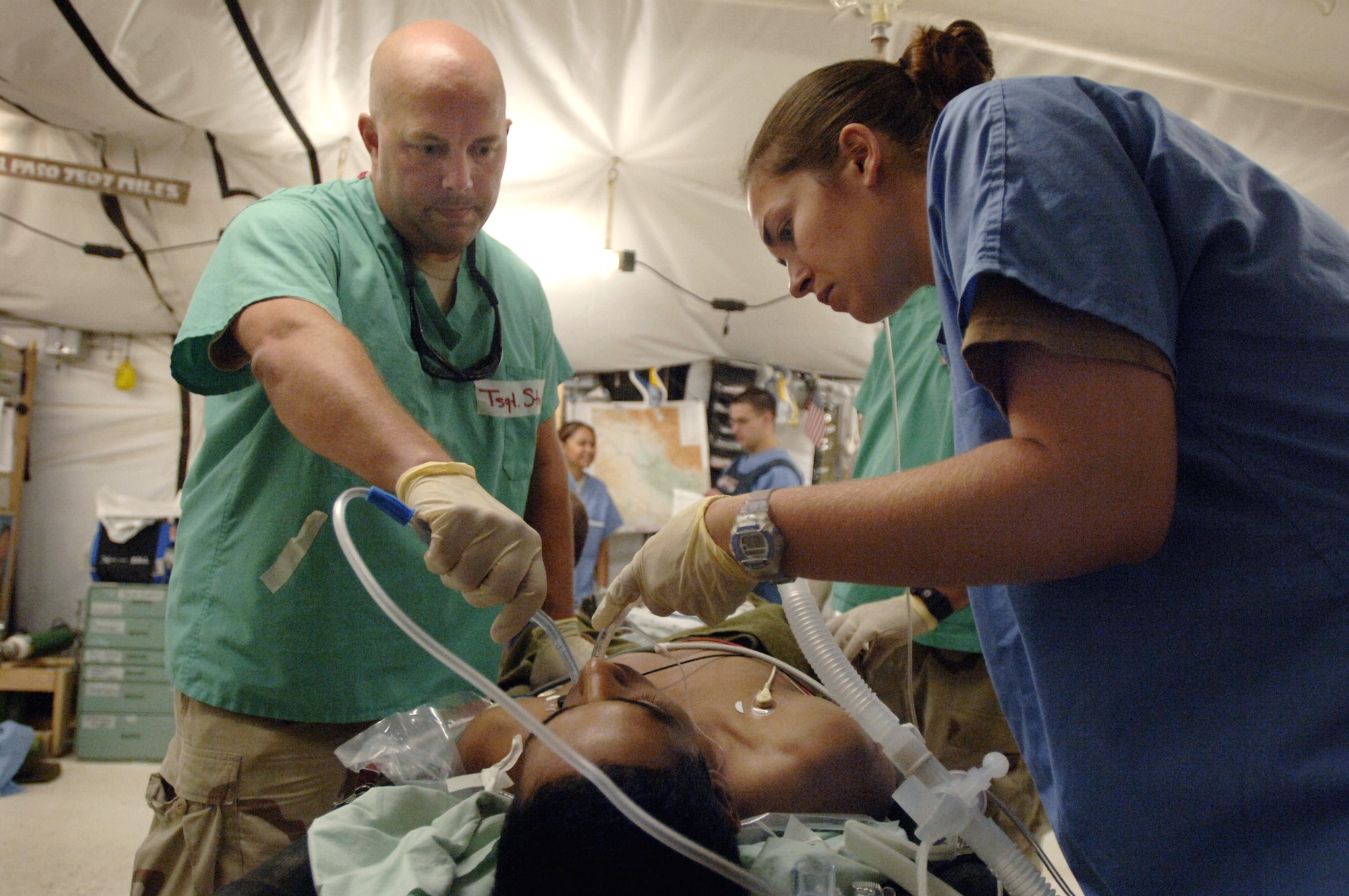 During his day off from work, Tech. Sgt. Ronald Stokes assists medical technician Senior Airman Brynn Delano in the care of a patient as a volunteer in the Air Force Theatre Hospital at Balad Air Base, Iraq.  Sergeant Stokes is an F-16 Fighting Falcon crew chief deployed from the 138th Fighter Wing in Tulsa, Okla.  (U.S. Air Force photo/Master Sgt. Scott Wagers)