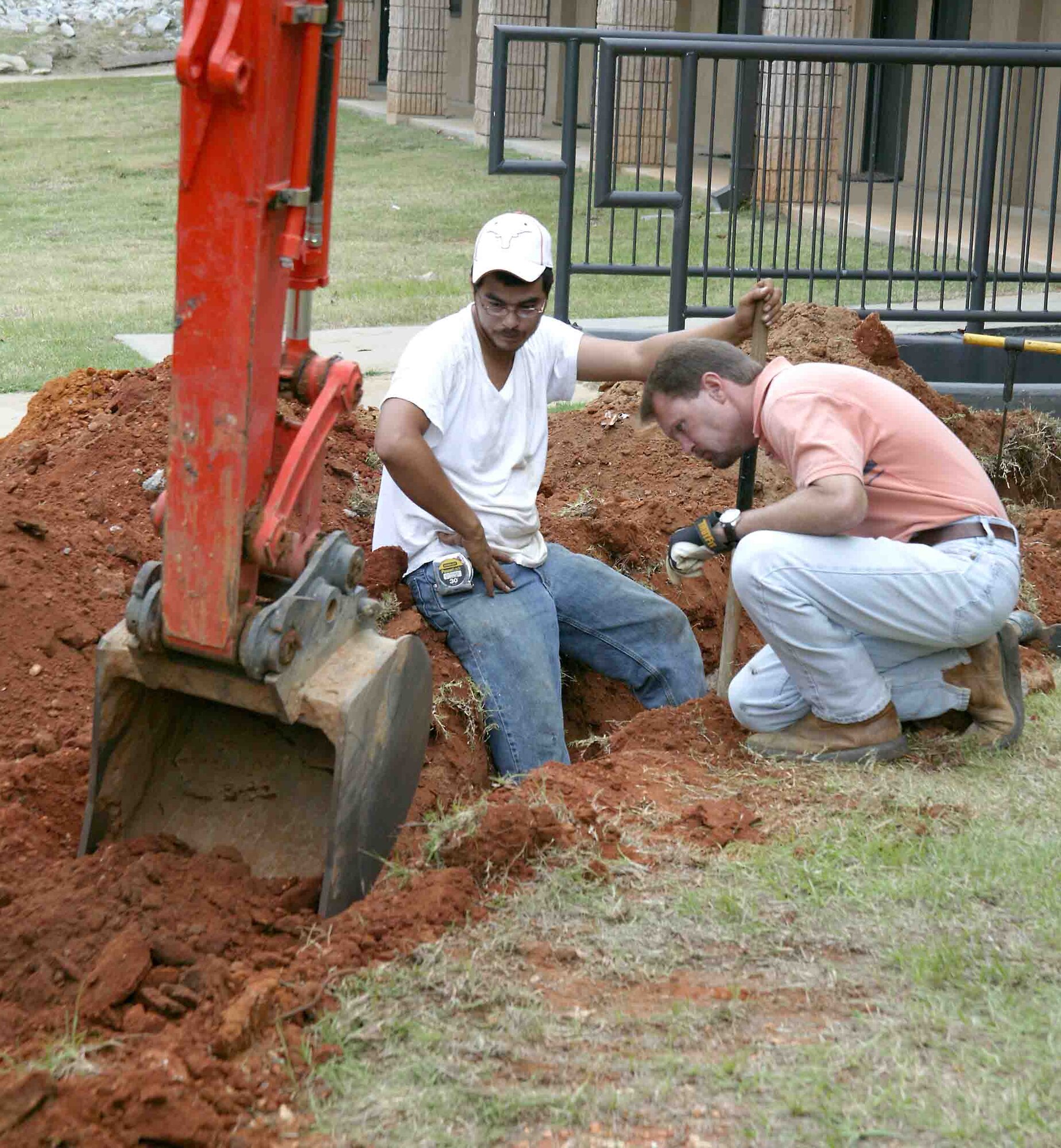 Elmer Delara (left) and Johnny Floyd, 20th Civil Engineer Squadron contractors from Energy Systems Group, watch carefully as the backhoe digs a hole for installation of a gas line for the new dormitory heaters Friday. The contractors watch closely to make sure the claw doesn't damage a buried electric line. (U.S. Air Force photo/Senior Airman John Gordinier)
