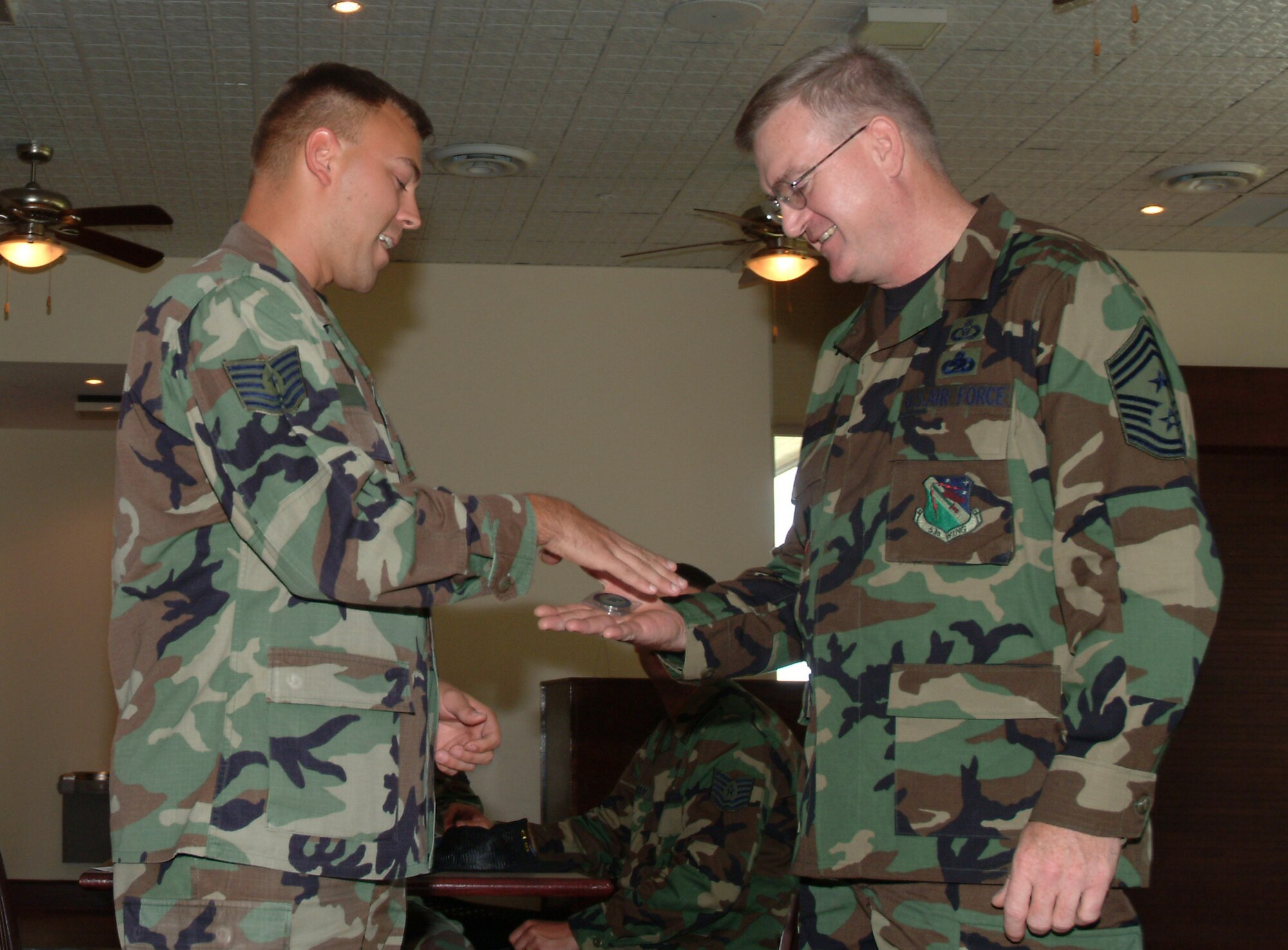 Tech Sgt. Brian Hill, 53d Top Four vice president, presents a Top Four coin and a handshake-welcome to Chief Master Sgt. Randy Salefske, the 53d Wing's new command chief Tuesday at the enlisted club. This assignment marks Chief Salefske's first command chief position.  He comes to the wing from 9th Air Force, Shaw AFB S.C.