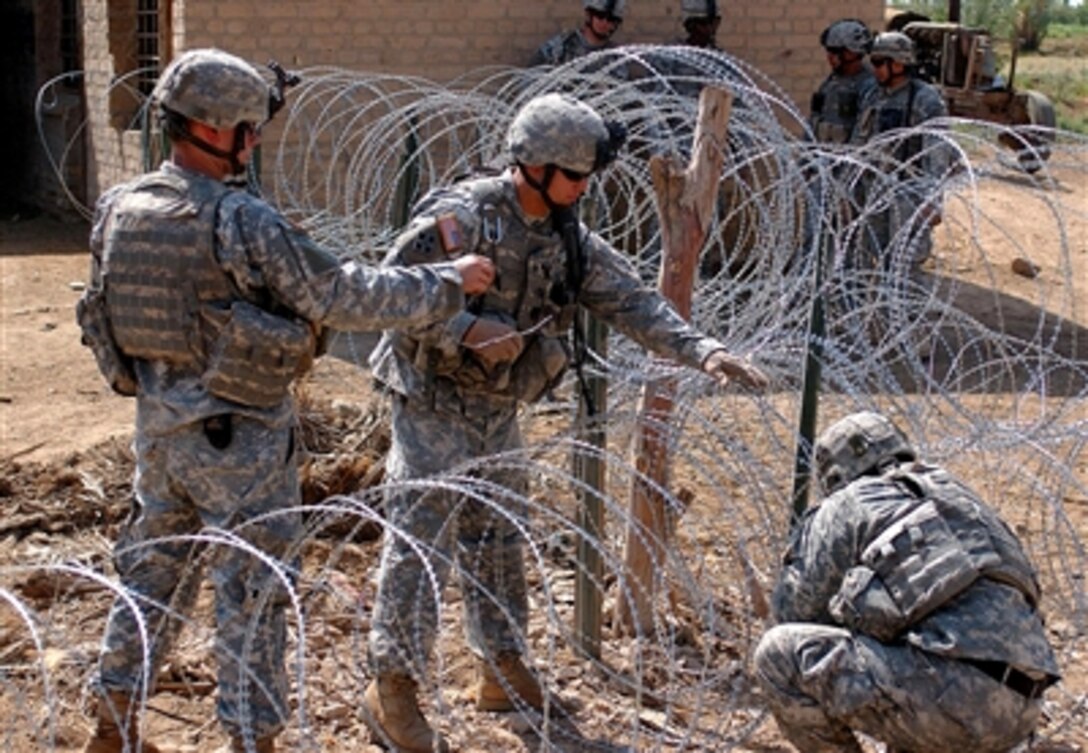 Soldiers from Company B, 2nd Battalion, 8th Infantry Regiment, 2nd Brigade Combat Team, 4th Infantry Division, build a temporary security fence around an equipment storage building in Muehla Oct. 16, 2006.

