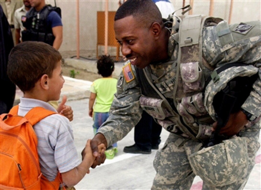 U.S. Army Sgt. Maj. Benny Hubbard shakes hands with an Iraqi child prior to the ribbon cutting for the Salah Hadi Obid Elementary School in Afak, Iraq, Oct. 12, 2006.