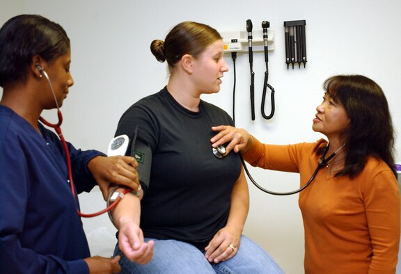 Gina Atkinson, right, the new family nurse practitioner in the 97th Medical Group, and licensed practical nurse Betty Gibson, left, examine a patient in the Family Practice Clinic Tuesday.  The addition of Ms. Atkinson to the medical staff allows the 97th MDG to once again provide women's health services. (U.S. Air Force photo by Staff Sgt. Monique Randolph)