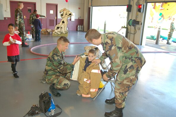 Andy Plant, son of Staff Sgt. Jonathan Plant, 436th Civil Engineer Squadron, tries on a fire-suit with the help of Senior Airman John Stortecky (left) and Airman 1st Class Derek Larson, 436th Civil Engineer Squadron firefighters. (U.S. Air Force photo/Staff Sgt. James Wilkinson)