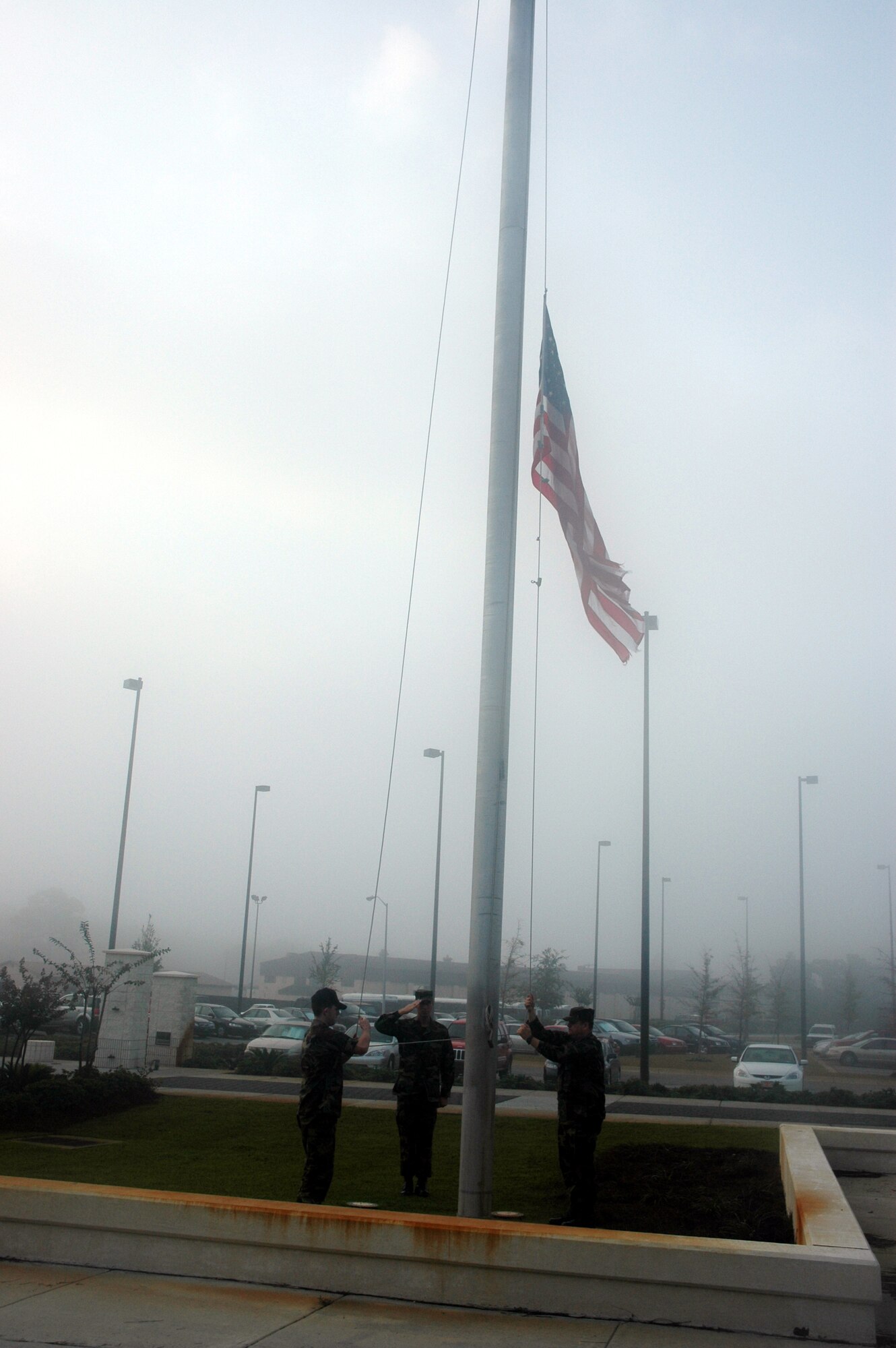 Chief Master Sgt. Todd Small, 16th Special Operations Wing command chief salutes as two Airmen lower the flag outside building 90210 Wednesday.  The flag was being replaced because storms on Tuesday caused it to shred. (U.S. Air Force Photograph by Jamie Haig)