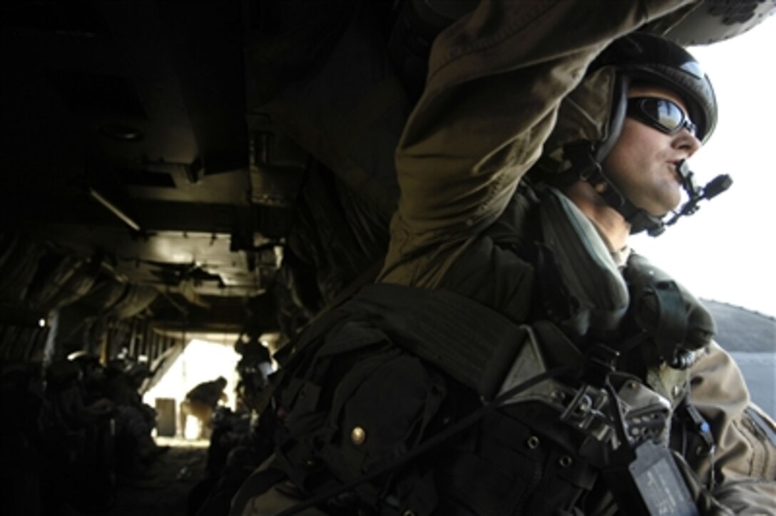 U.S. Navy Petty Officer 1st Class Joe Cox scans the skies from the door of an MH-53 Sea Dragon helicopter as it flies over Forward Operating Base Dagger in Kuwait on Oct. 19, 2006.  Cox and the rest of his crew are flying participants in the Joint Civilian Orientation Conference 72.  The JCOC is a program sponsored by the Secretary of Defense for civilian public opinion leaders interested in growing their knowledge of the military and national defense issues by traveling to overseas military bases. 