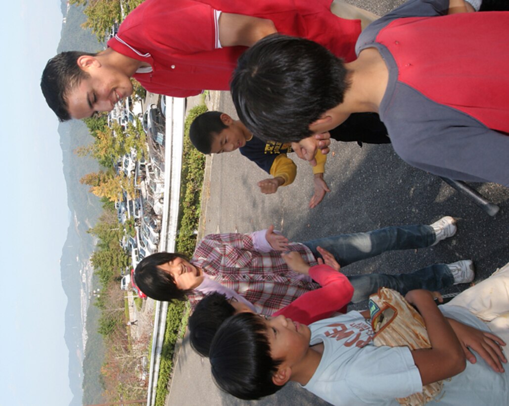 Seaman Kevin S. Dawson, Headquarters and Headquarters Boathouse engine man and San Antonio native, plays a Japanese form of rock, paper, scissors with children from the Yahata Children?s Home at Saiki Athletic Park in Hiroshima Oct. 21.