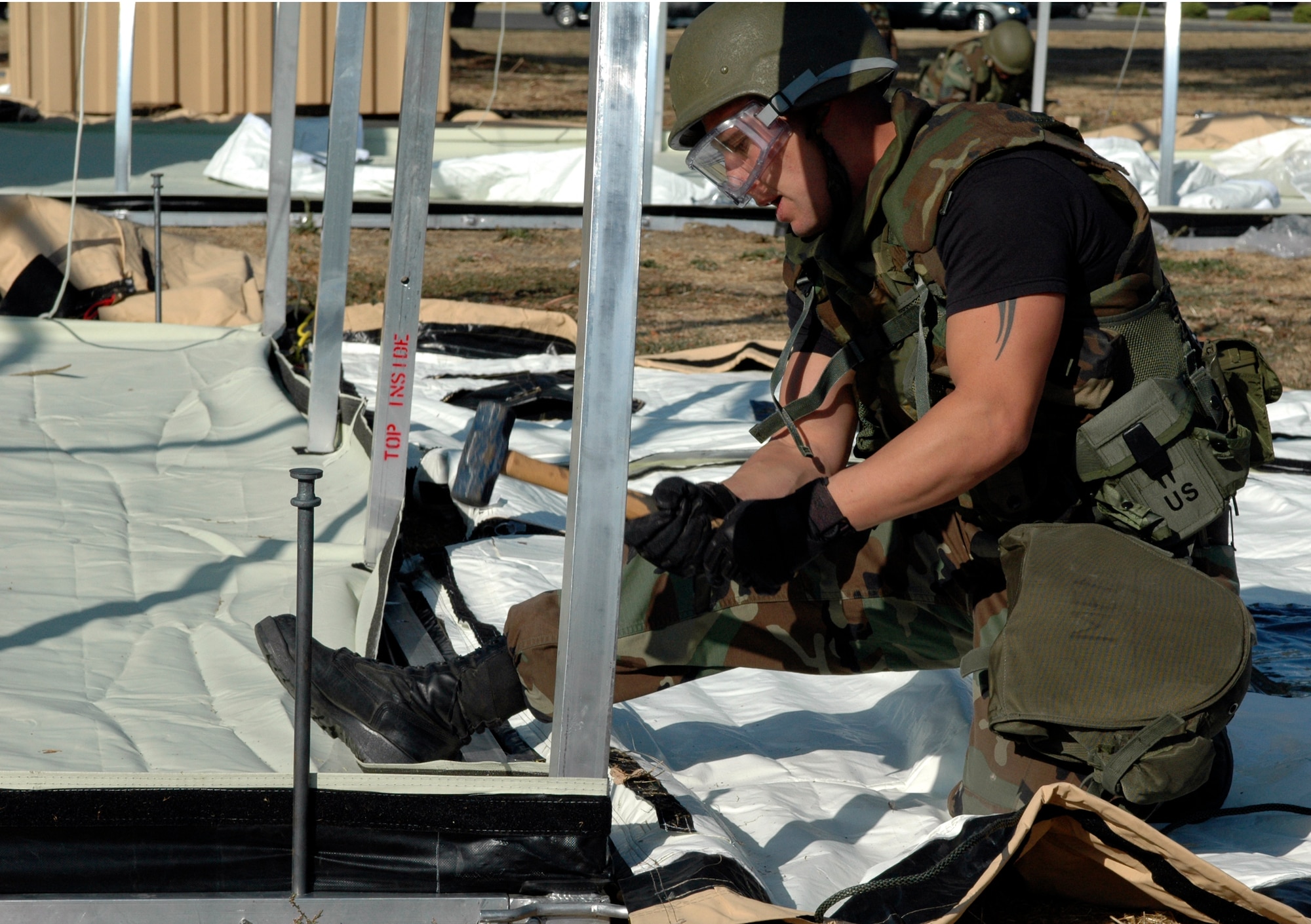 Senior Airman Robert Dempsey, 573rd Global Support Squadron, hammers tent stakes into the ground. These stakes help provide the stability that keep the structures standing for up to ten years. (U.S. Air Force photo by Jennifer Brugman/60th AMW Public Affairs)