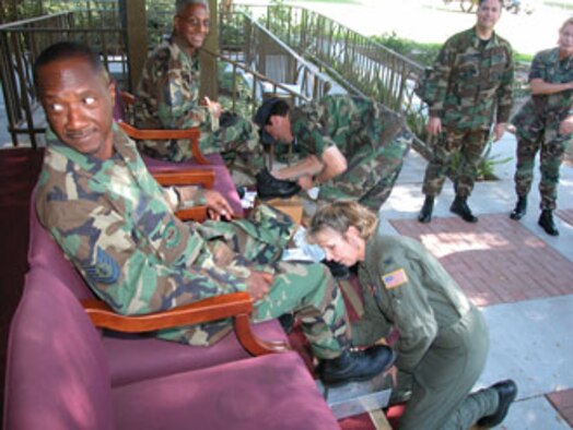 Col. Jeff Barnson, 452nd Air Mobility Wing vice commander, polishes the boots of Master Sgt. Michael Johnson, 56th Aerial Port Squadron, while Col. Heather Cosmas, 452nd Aeromedical Evacuation Squadron commander, foreground, applies wax to  452nd Services Flight Tech. Sgt. Marvin Anderson’s boots.  Commanders from around the wing turned up at a shoe shine fundraiser during the October drill at the dining facility on base to help defray the ticket cost of the upcoming March Field Military Ball for the wing's more junior reserve Airmen.  Senior leaders raised $700 for their spit and polish effort.  (U.S. Air Force photos by TSgt Mike Blair, 452 AMW/PA)