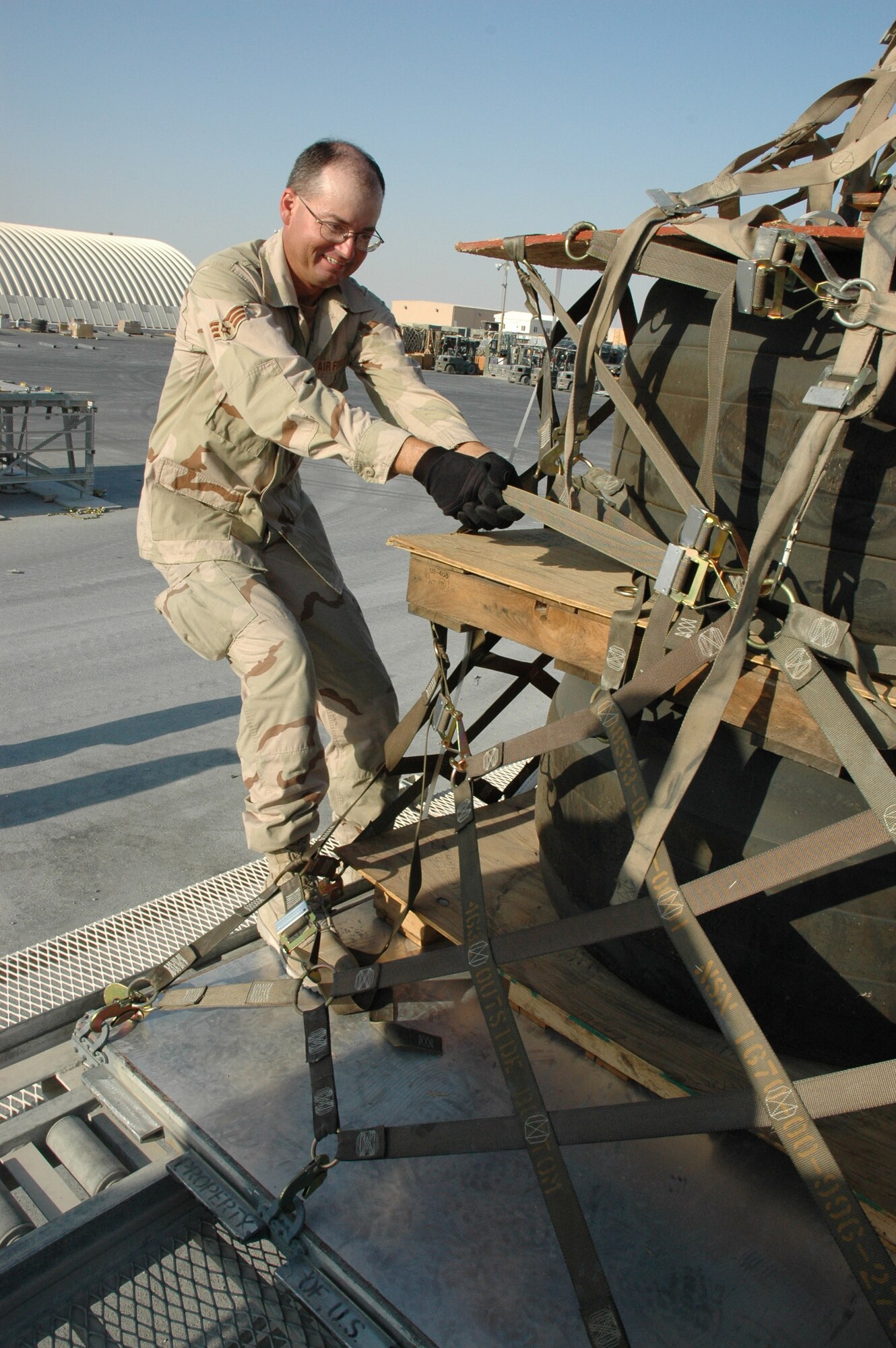 Senior Airman Jayson Steelman puts his back into tightening the side nets on a multi-pallet "train".  Airman Steelman, along with other Airmen in the 8th Expeditionary Air Mobility Squadron, developed a more efficient way to palletize aircraft tires which will save the Air Force some $14,700 a month.  Airman Steelman is a Texas Air National Guardsmen deployed to the 8th EAMS in Southwest Asia.  (U.S. Air Force photo/Maj. Ann P. Knabe)