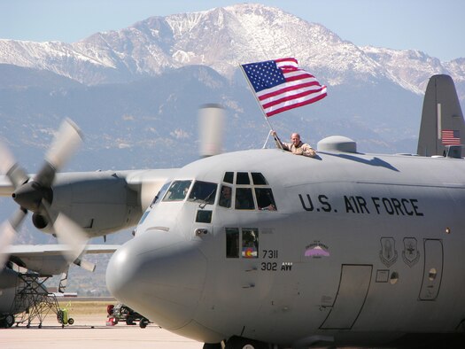 PETERSON AIR FORCE BASE, Colo. (AFRC) -- Maj. Stephen Stelly, 731st Airlift Squadron flight commander, proudly displays the American flag as a 302nd Airlift Wing C-130 taxis past Pikes Peak during a recent homecoming. On Oct. 4, wing members ended 14 months of deployments in support of U.S. Central Command operations in Southwest Asia. (U.S. Air Force photo by Master Sgt. Mark Clark)