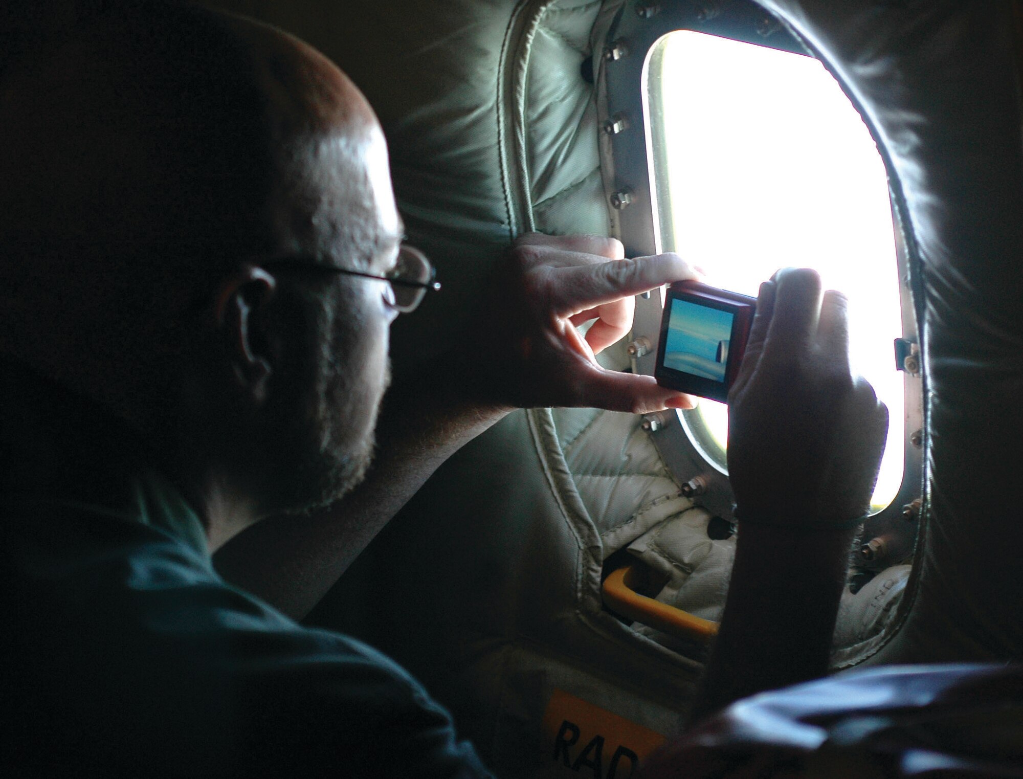 Richard Fish, Chirping Bird Productions, takes a photograph out the window of the KC-135 aircraft. (U.S. Air Force photo/Staff Sgt. Tallace Encalade)