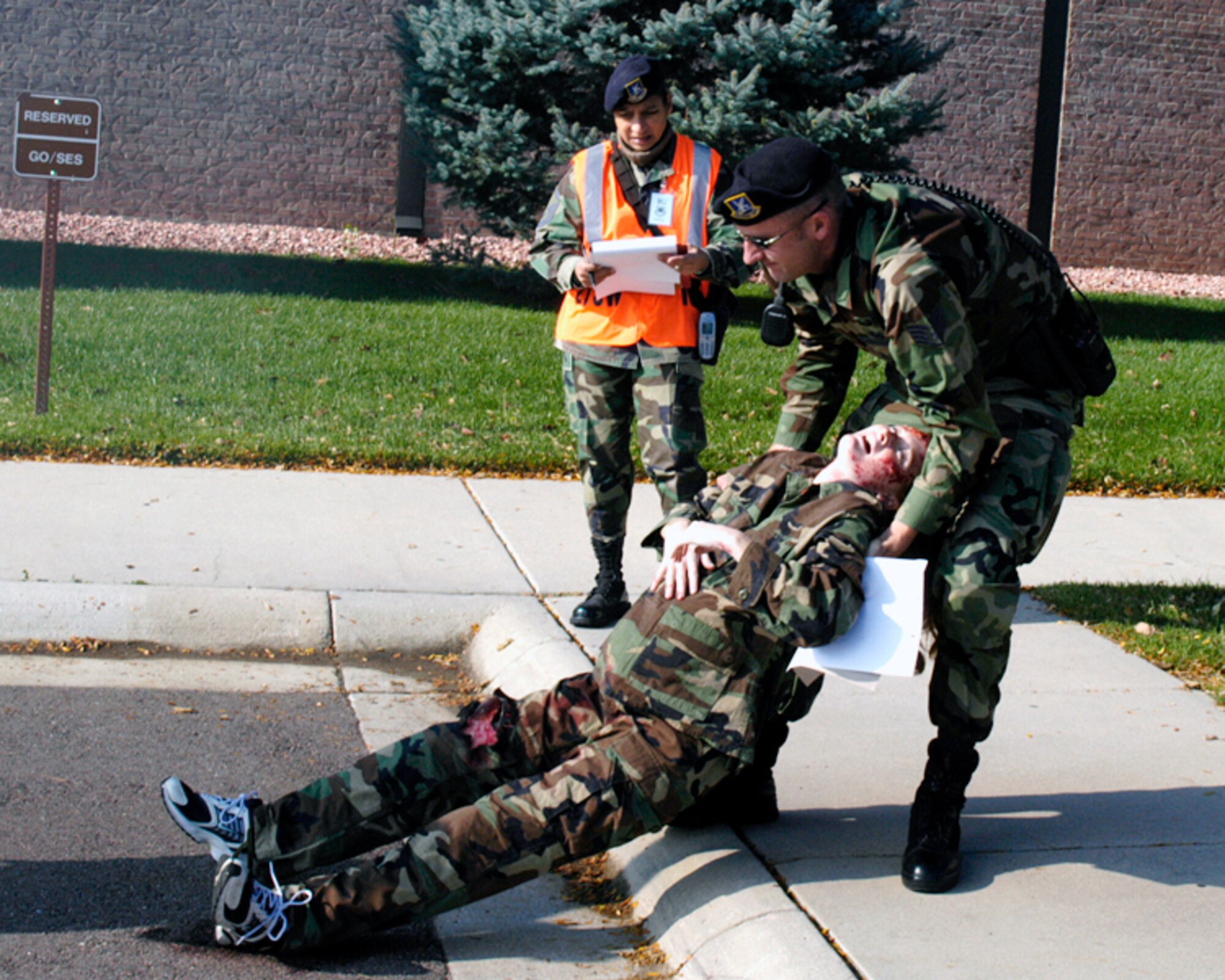 Staff Sgt. Jason Adams, 21st Security Forces patrolman, drags a "victim" to safety during the Operational Readiness Inspection Oct. 11, as Master Sgt. Nancy Altenbernd inspects his work. Sgt. Adams was the first patrolman on scene and triaged eight victims, provided Self Aid and Buddy Care, then relayed the victims' injuries to the arriving fire chief and medical teams.
(U.S. Air Force photo by Joe Fischer)    