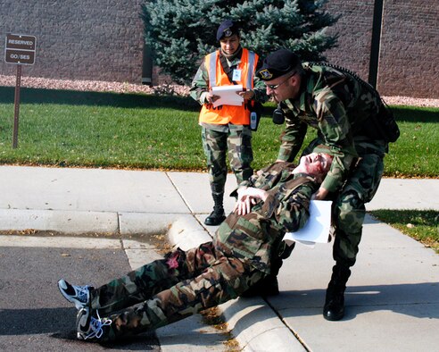 Staff Sgt. Jason Adams, 21st Security Forces patrolman, drags a "victim" to safety during the Operational Readiness Inspection Oct. 11, as Master Sgt. Nancy Altenbernd inspects his work. Sgt. Adams was the first patrolman on scene and triaged eight victims, provided Self Aid and Buddy Care, then relayed the victims' injuries to the arriving fire chief and medical teams.
(U.S. Air Force photo by Joe Fischer)    