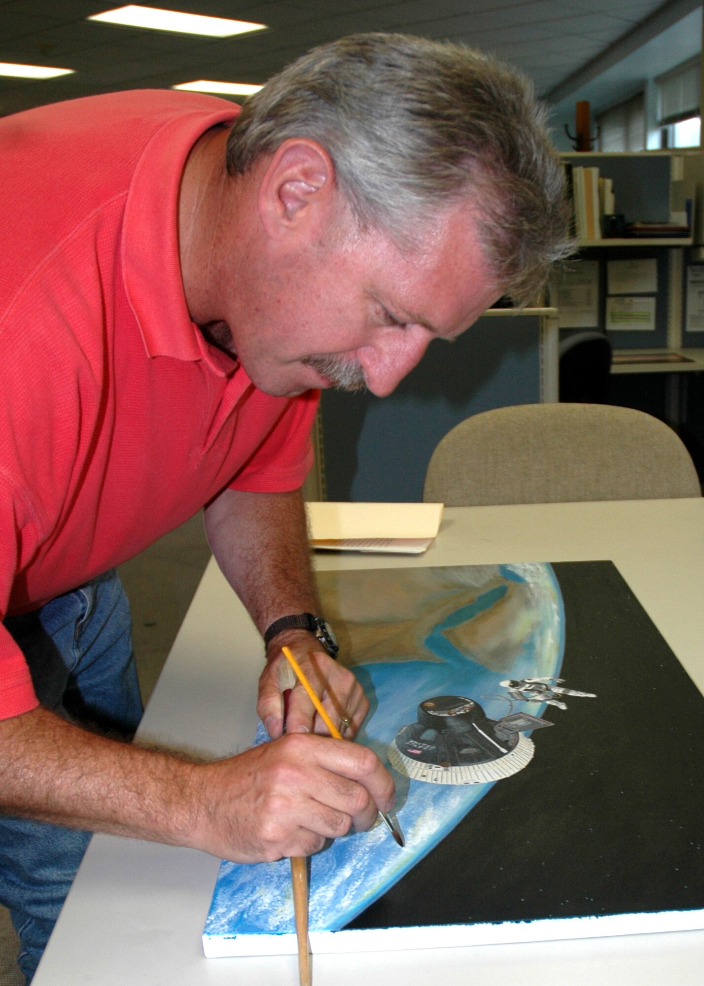 WESTOVER AIR RESERVE BASE, Mass. -- Christopher Doyle, an artist from Westover, applies the final touches to his painting of Air Force Maj. Edward H. White II conducting the first extra vehicular activity for the US manned space flight program in June 1965. Mr. Doyle chose this historical event as part of the 60th anniversary of the Air Force. He is also a senior master sergeant with the Air Force Reserve’s 439th Maintenance Squadron at Westover. He attended the anniversary celebration and ribbon-cutting at the Pentagon Oct. 19. Mr. Doyle's painting will be displayed in Washington, D.C. through this next year. (U.S. Air Force photo by Tech. Sgt. Andrew Biscoe)