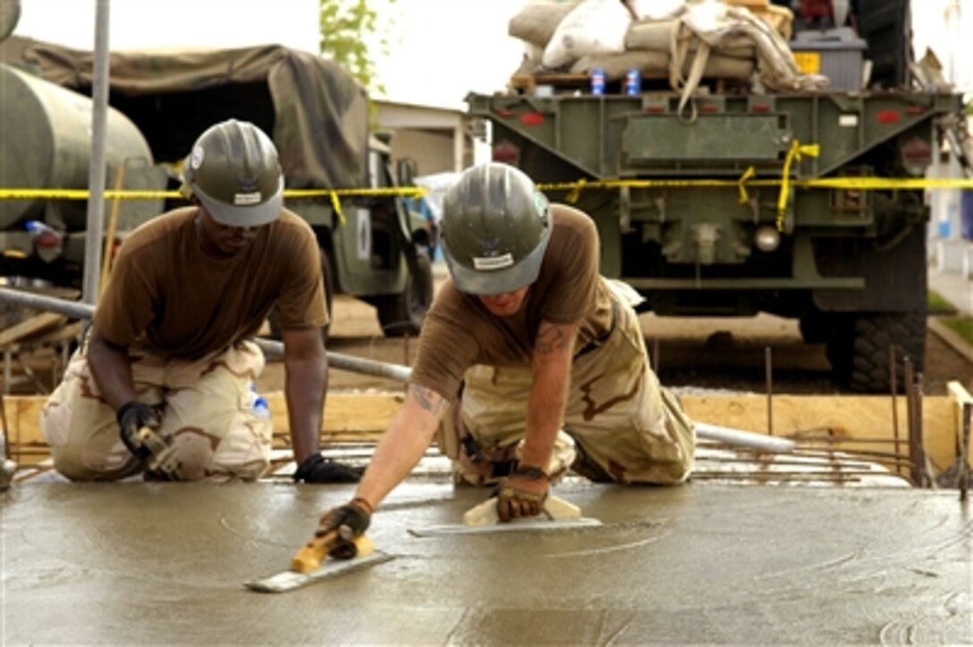 U.S. Navy Utilitiesman Bryon McMath and Steelworker Jerrod Johnson level cement using magnesium trowels Oct. 11, 2006, during the construction of a bathroom at the village schoolhouse in Balbala, Djibouti. McMath and Johnson are assigned to the Naval Mobile Construction Battalion 5.  