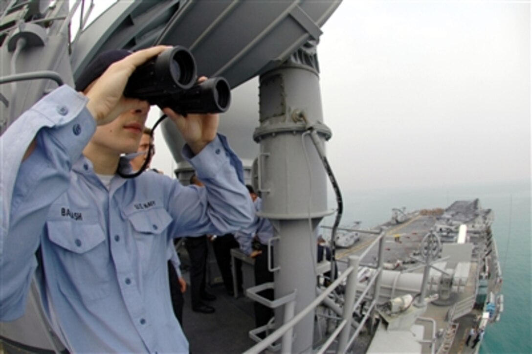 U.S. Navy Seaman Joshua Balash stands as lookout watch onboard the USS Boxer as it pulls into Changi Naval Base, Singapore, for a port visit, Oct. 12, 2006. Boxer is the flagship of Boxer Expeditionary Strike Group operating out of San Diego, Calif. 
