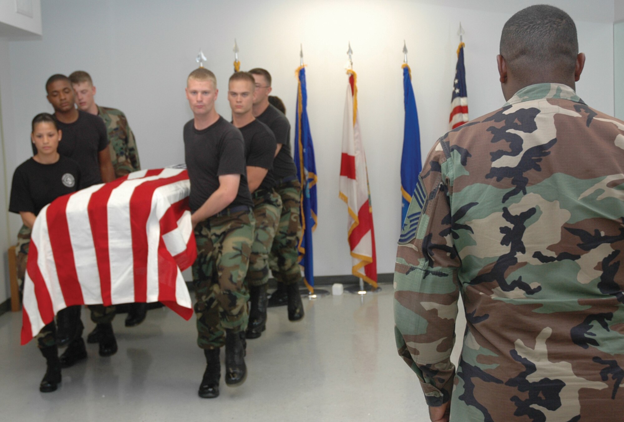 TYNDALL AFB, Fla. --  Chief Master Sgt. Mark Charles, right, 325th Communications Squadron chief enlisted manager, stands in position as the Honor Guard marches forward carrying a casket during practice. Chief Charles is an honorary Honor Guard member who will perform during funerals to honor fellow enlisted members. (U.S. Air Force photo by 1st Lt. Amanda Ferrell)