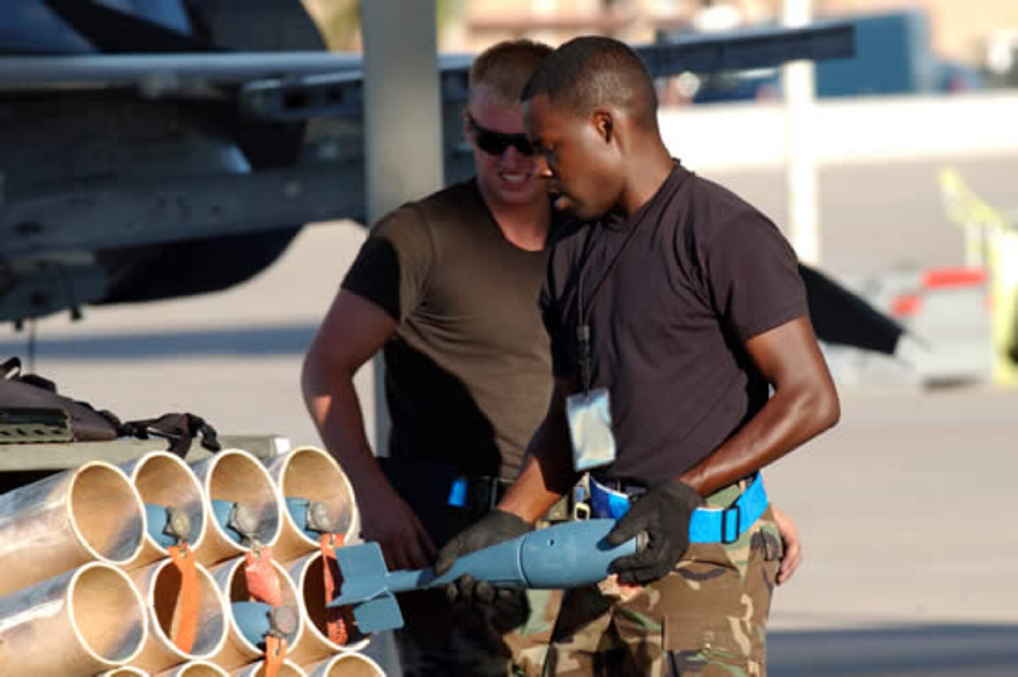 Senior Airman James Mitchell and Airman 1st Class Quincy Leslie, weapons specialists with the 62nd Aircraft Maintenance Unit, transfer BDU-33 practice bombs to another aircraft during routine flight operations. (U.S. Air Force photo/Tech. Sgt. Angela Clemens)