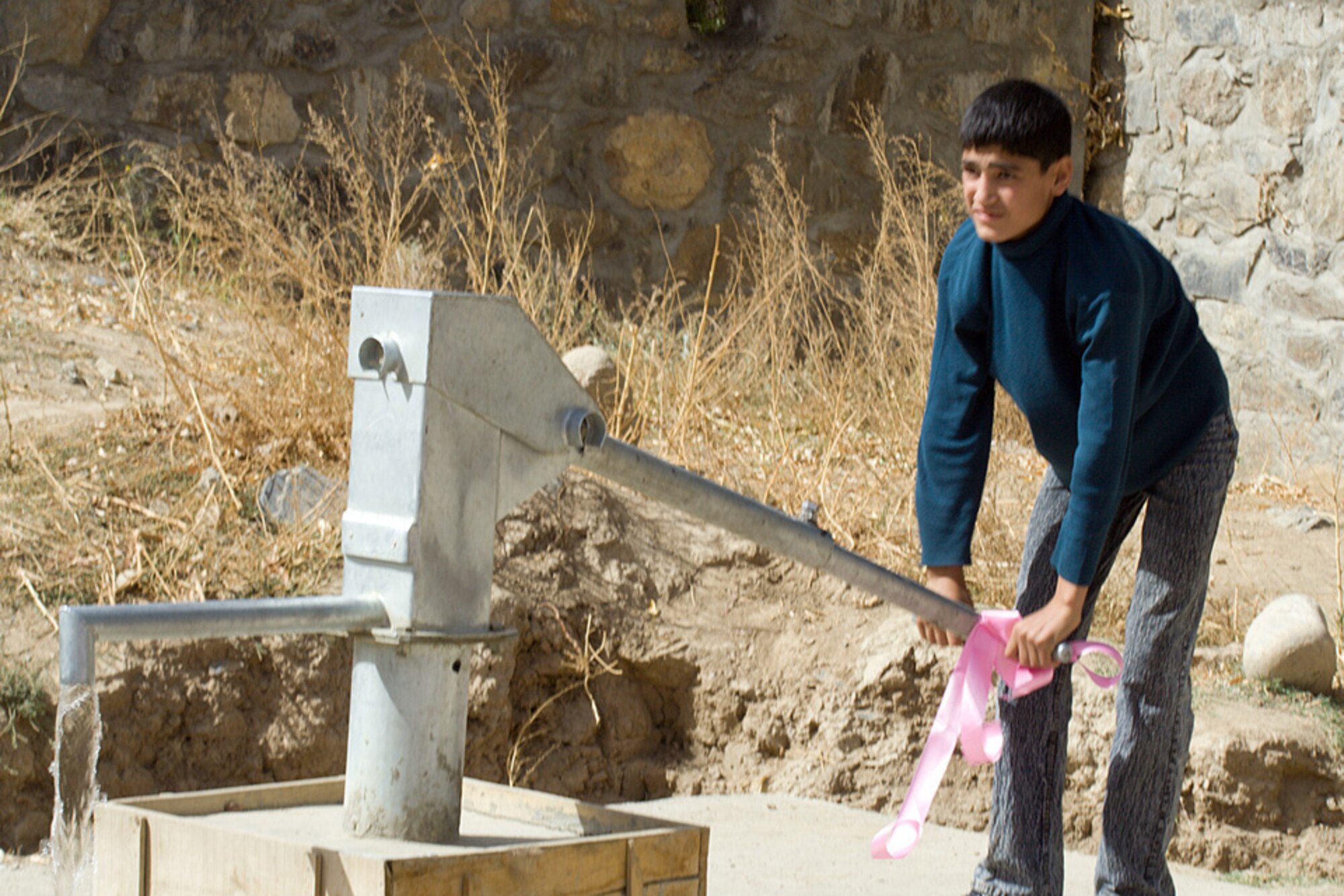 A student at the Rohka School demonstrates the new well pump built by the Panjshir Provincial Reconstruction Team and dedicated Oct. 21.  The well was funded by the Panjshir Provincial Reconstruction Team's Commander's Emergency Response Program funds. (Air Force photo\Tech. Sgt. John Cumper).