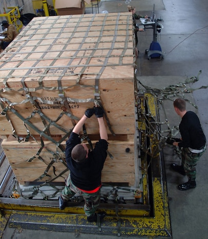 Airmen from the 437th Aerial Port Squadron tie down netting to secure pallets carrying "up armor" kits being transported to areas in Southwest Asia, at Charleston Air Force Base, S.C., on Oct. 25, 2006. Up armor kits are used on HMMWVs to help protect them from improvised explosion devices. (U.S. Air Force photo/Tech. Sgt. Larry A. Simmons)