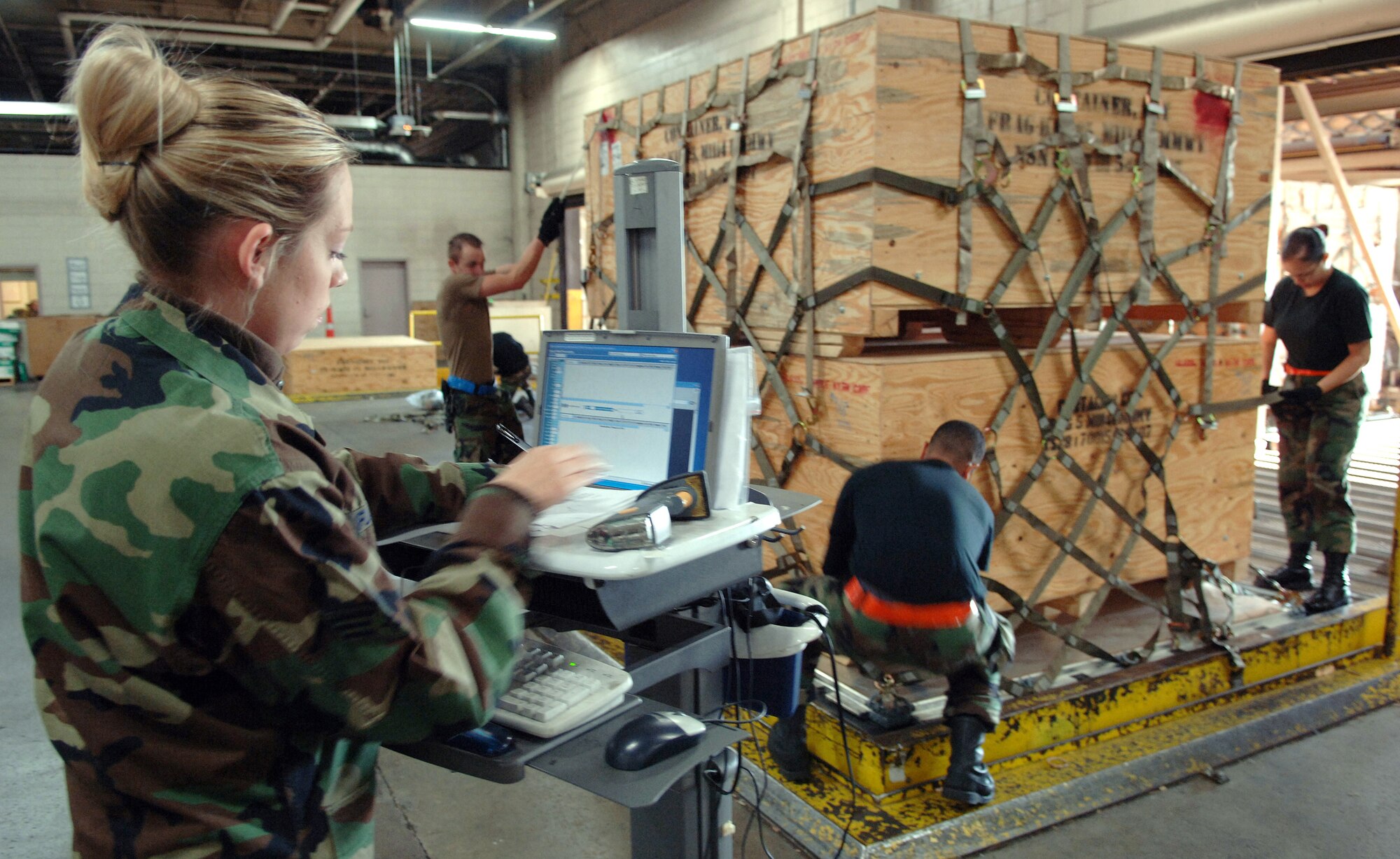 Senior Airman Cecilia Fuller, foreground, checks the cargo pallet content listing to ensure all pallets are properly labeled while fellow airmen strap netting down to secure cargo to the pallet at Charleston Air Force Base, S.C., Oct. 25, 2006. Airman Fuller is an air transportation specialist with the 437th Aerial Port Squadron, Charleston Air Force Base, S.C. (U.S. Air Force photo/Tech. Sgt. Larry A. Simmons)