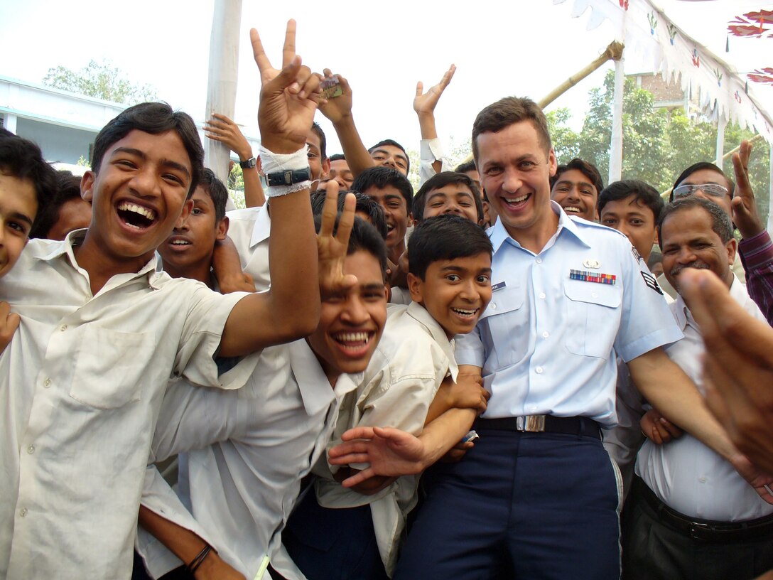 Senior Airman Vladimir Tchekan, recently promoted to staff sergeant, visits with school children while touring with the U.S. Air Force Band of the Pacific-Asia in Bangladesh earlier this year. The band played with the Bangladesh Armed Forces Band. (U.S. Air Force photo)