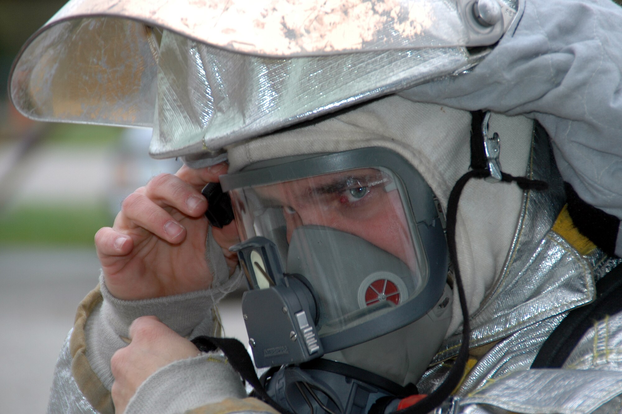 WRIGHT-PATTERSON AFB, Ohio -- Firefighter SrA Glen Beddies Jr., from the 445th Civil Engineer Squadron's Fire Protection Flight dons his mask before entering a dense smoke filled building.  The airman was one of seven firefighters who had to work as a team to ascertain the situation upon arriving at the scene then safely and quickly save those inside and then put out the fire. (U.S. Air Force Photo/Tech. Sgt. Charlie Miller).