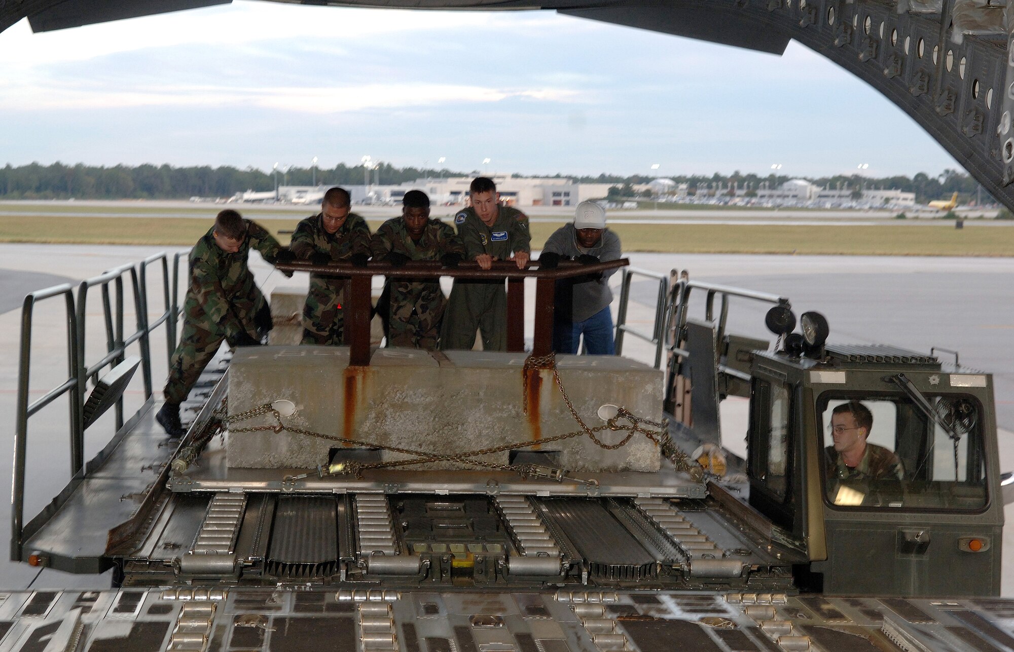 Airman 1st Class Derrick Maloney, second from right, and ramp loaders from the 437th Aerial Port Squadron, push cargo onto a C-17 Globemaster III at Charleston Air Force Base, S.C., Oct. 26. Airman Maloney is a loadmaster with the 17th Airlift Squadron. (U.S. Air Force photo/Tech. Sgt. Larry A. Simmons)