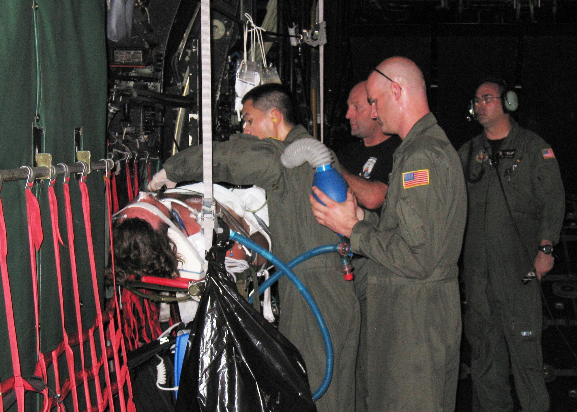 Staff Sgt. Darren Pon administers aid to the patient as Master Sgt. Eric Degner and Senior Master Sgt. Simmons provide support. Loadmaster, Master Sgt. Michael Henry, stands by in the background to assist as needed. (U.S. Air Force photo/Tech. Sgt. Elliott Paige)