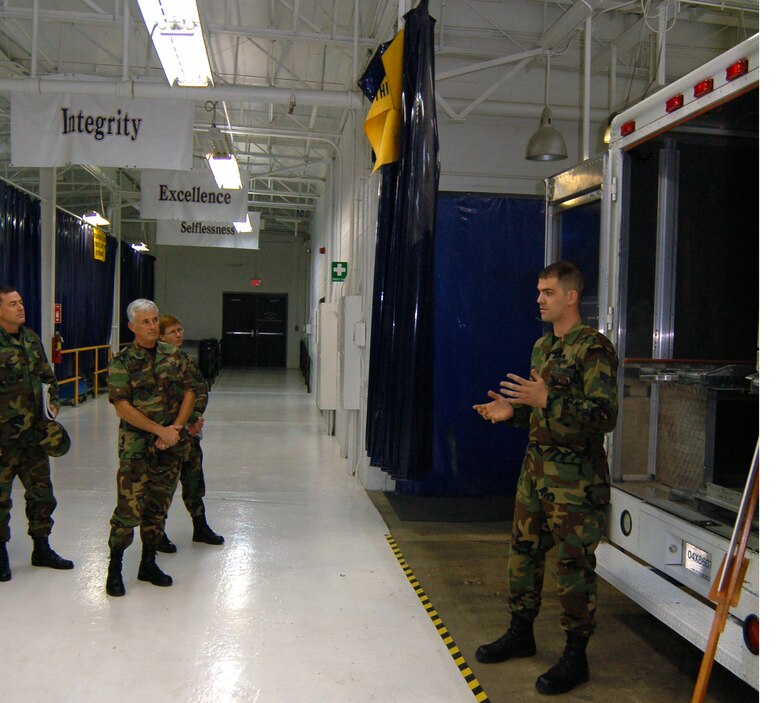 Airman 1st Class William Werner (right), 436th Maintenance Squadron aircraft metals technologist, briefs Col. William Wootton, Air Mobility Command Maintenance Division chief and Daedalian Award Team chief, and the rest of his team at the “Monster Garage” in Building 721 here Monday about various modifications to vehicles at Dover to increase load capacity and improve loading systems. Dover is one of three AMC bases in the running for the Maj. Gen. Clements McMullen Memorial Weapons System Maintenance Trophy. The award is presented annually to a U.S. Air Force unit at the wing level for having the best weapon system maintenance record for the preceding calendar year. This is the first time Dover AFB has been a finalist for the award since 1986.  The AMC Daedalian Award Team arrived here Sunday for a two-day tour of various facilities to observe the integration of maintenance with the total wing mission. The team’s itinerary included the “Monster Garage,” Isochronal Inspection Dock, Air Force Smart Operations 21 classroom, Combined Avionics System Trainer, and all other maintenance related facilities. (U.S. Air Force photo/Staff Sgt. James Wilkinson)