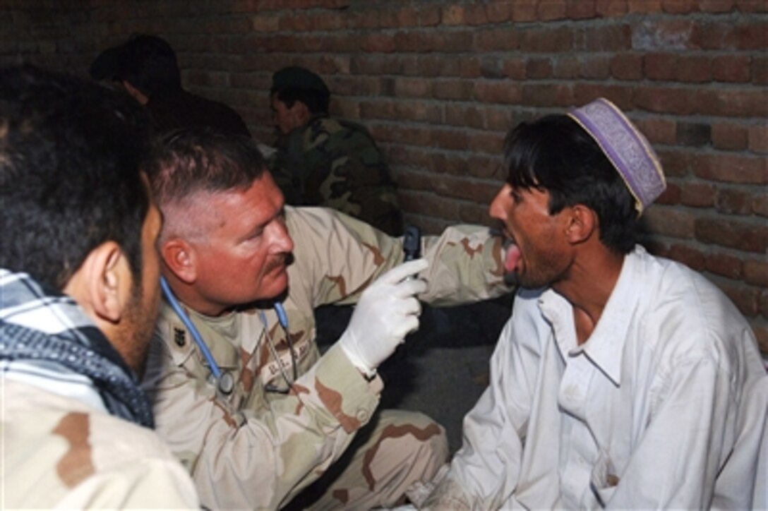 U.S. Navy Master Chief Petty Officer Rick Wilson examines the throat of a young Afghani man during a medical civic action project in the village of Dur Baba, Afghanistan, on Oct. 17, 2006.  Wilson is attached to the Cooperative Medical Assistance team of Combined/Joint Task Force-76 who co-sponsored the project with the Jalalabad Provisional Reconstruction Team.  