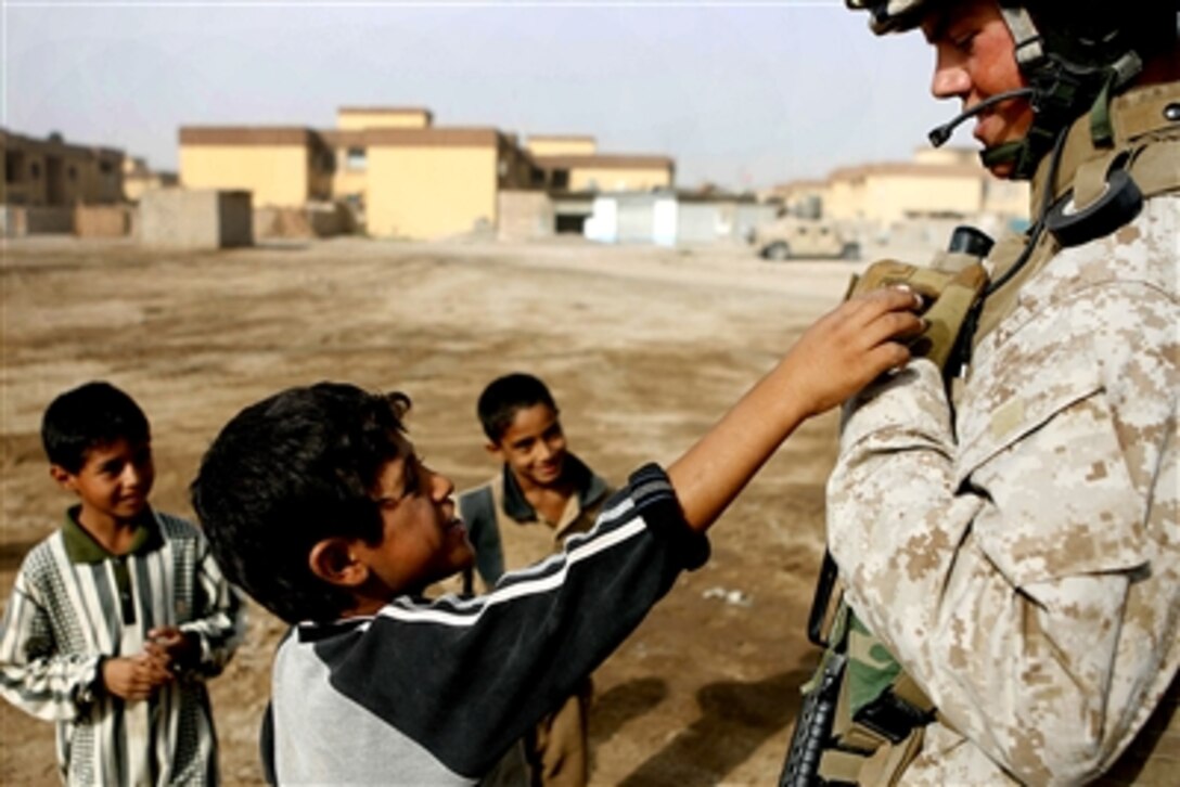 U.S. Marine Corps Cpl. Justin P. Wilson, a motor-vehicle operator with Engineer Support Company, 9th Engineer Support Battalion, 1st Marine Logistics Group (Forward), interacts with Iraqi children at a construction site in Habbaniyah, Oct. 23, 2006.