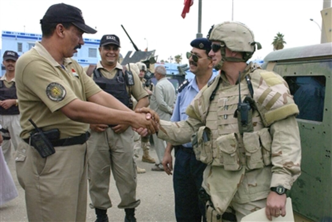 U.S. Army Staff Sgt. Bill Straily, right, shakes hands with the an Iraqi Police SWAT team deputy commander on Oct. 22, 2006, in Diwaniyah, Iraq. U.S. forces had just provided the Iraqi SWAT team with 100 new uniforms.