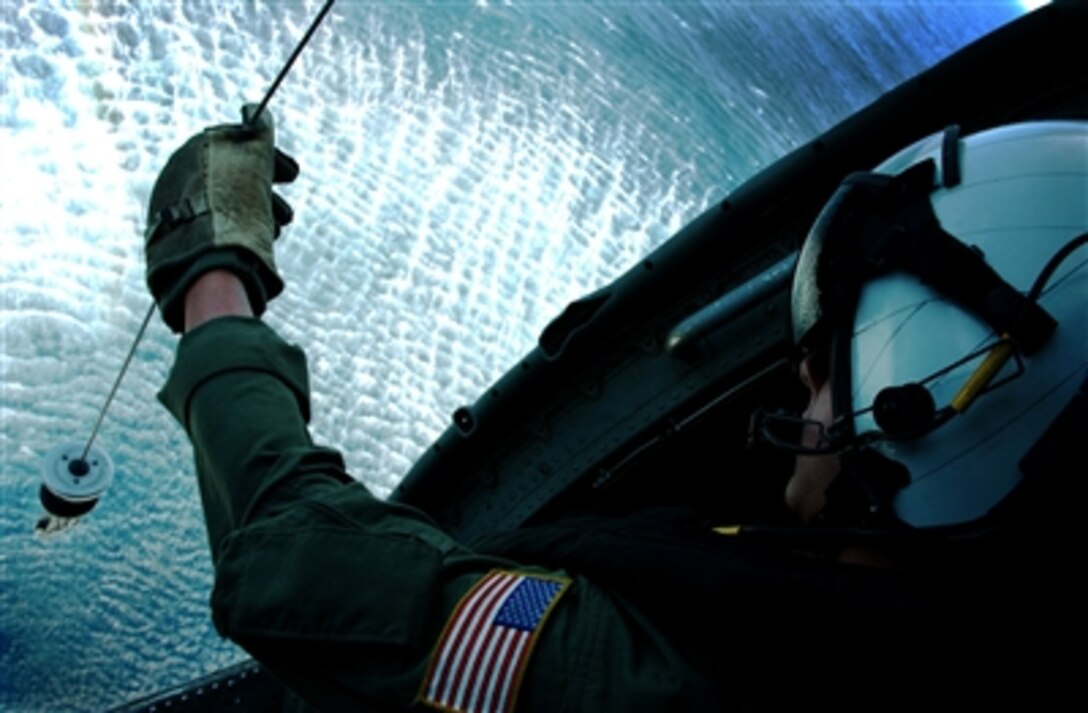 Petty Officer 3rd Class Kelvin Kolb lowers a sling as he and the crew of his SH-60 Seahawk helicopter practice search and rescue techniques off the coast of Southern California on Oct. 24, 2006.  Kolb, a U.S. Navy aviation warfare systems operator, is attached to Helicopter Anti-Submarine Squadron 4, deployed aboard the USS Ronald Reagan (CVN 76).  