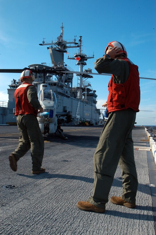 ABOARD USS BOXER, At Sea (Oct. 27, 2006) - An Aviation Ordnance Marine assigned to Marine Medium Helicopter Squadron 165 (Reinforced), 15th Marine Expeditionary Unit (Special Operations Capable) aboard USS Boxer (LHD 4) directs the execution of "hot-loading" a AH-1W Super Cobra helicopter during Malabar 2006.  Hot-loading is loading ammunition onto an aircraft with engines running.  Malabar 2006 is the first time the Navy and Marine Corps completed a hot-load at sea.  Malabar 2006 is a multinational exercise between the U.S., Indian and Canadian armed forces to increase interoperability between the three nations and support international security cooperation missions.
