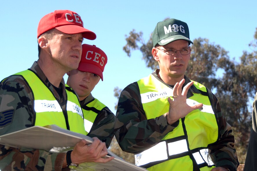 Tech. Sgt. Daniel Wyrick and Airman 1st Class Bernard Mutz, 60th Civil engineer Squadron listen to Col. Stephen Shea, 60th Mission Support Group commander, as he provides inputs as Exercise “Aircraft Down” unfolds. More than 350 people, including local law enforcement and Red Cross volunteers, took part in the exercise. (U.S. Air Force photo by Nan Wylie)