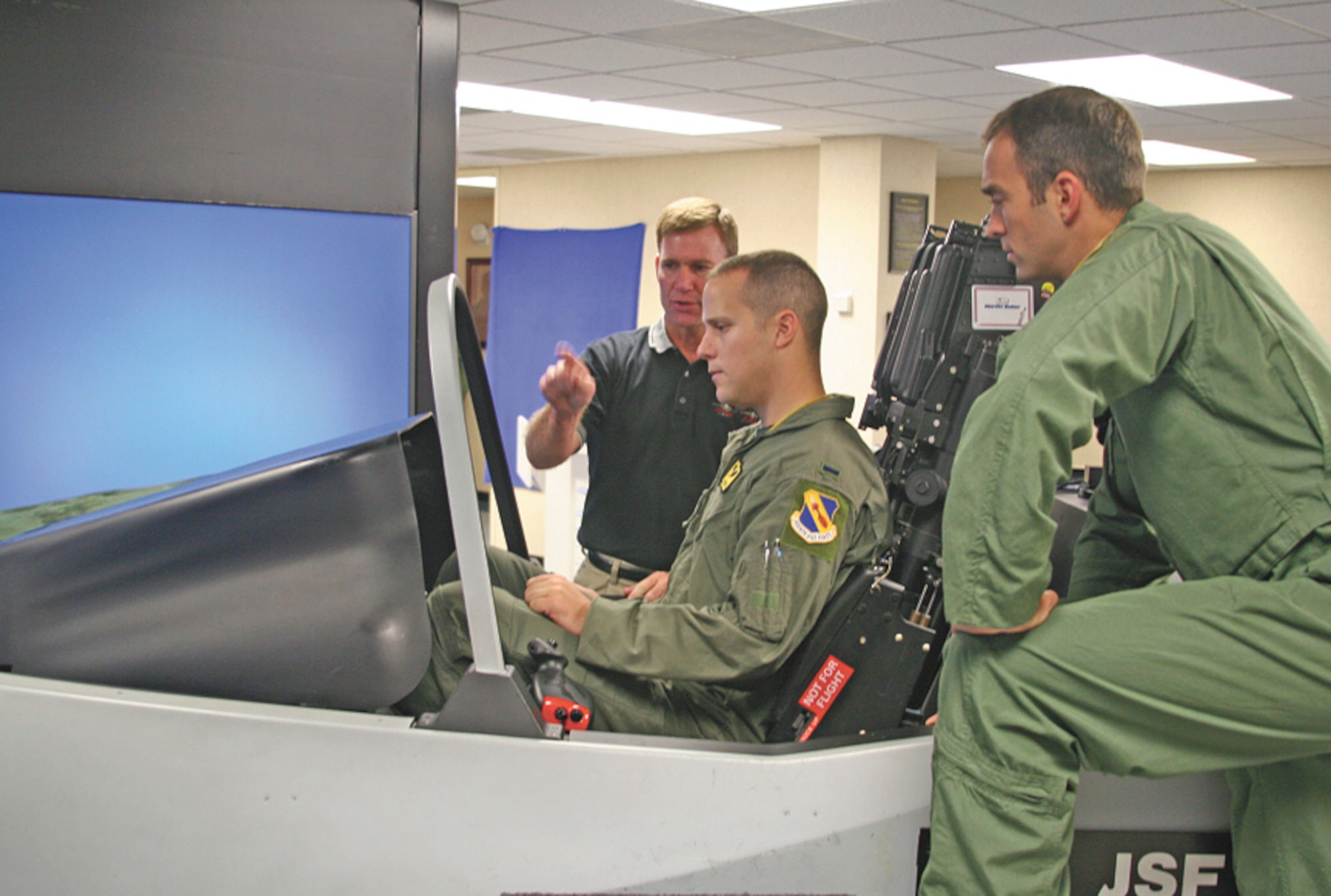 (Right) Capt. Matthew Phillips, a 335th Fighter Squadron pilot, looks on as Mike Barton, Lockheed Martin Pilot Vehicle Interface expert, gives a cockpit overview of the F-35 Lightening II simulator to 1st Lt. Christopher Beery, a 335th Fighter Squadron weapons system officer.  Members of the 333rd, 334th, 335th and 336th fighter squadrons had an opportunity to get an up close view of what the F-35 has to offer in the way of the latest fighter technology.  (U.S. Air Force photo by Staff Sgt. Les Waters)