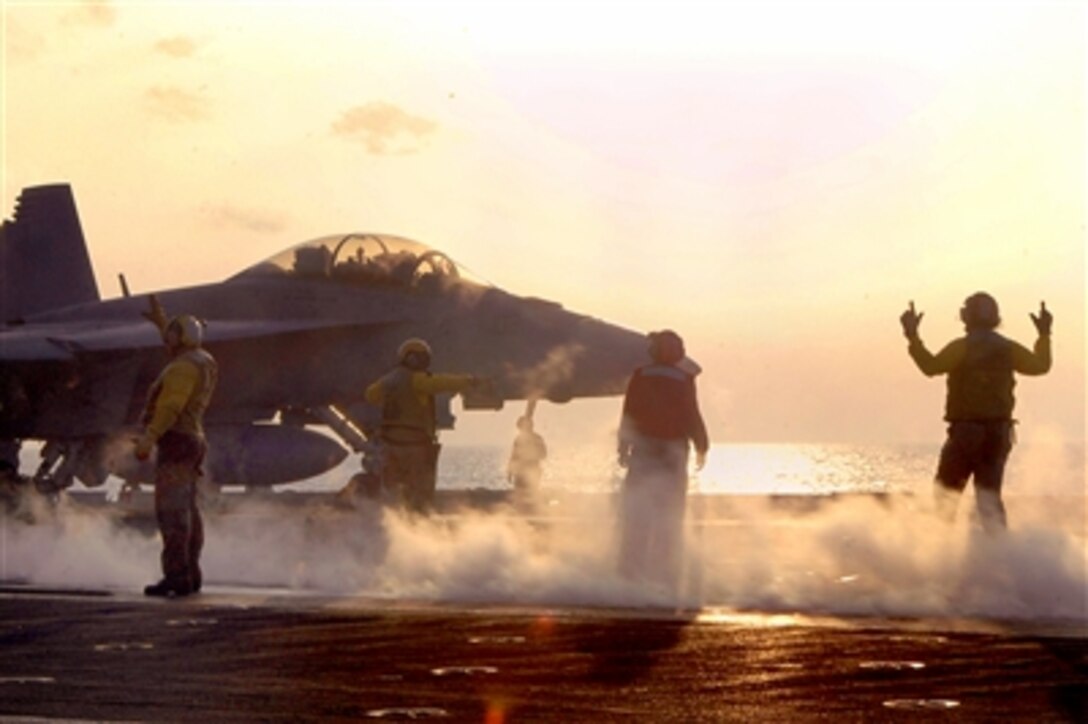 Aircraft directors signal an F/A-18F Super Hornet assigned onto a catapult in preparation for evening flight operations on the flight deck of USS Kitty Hawk, Oct. 24, 2006. The USS Kitty Hawk, is deployed off the coast of southern Japan.