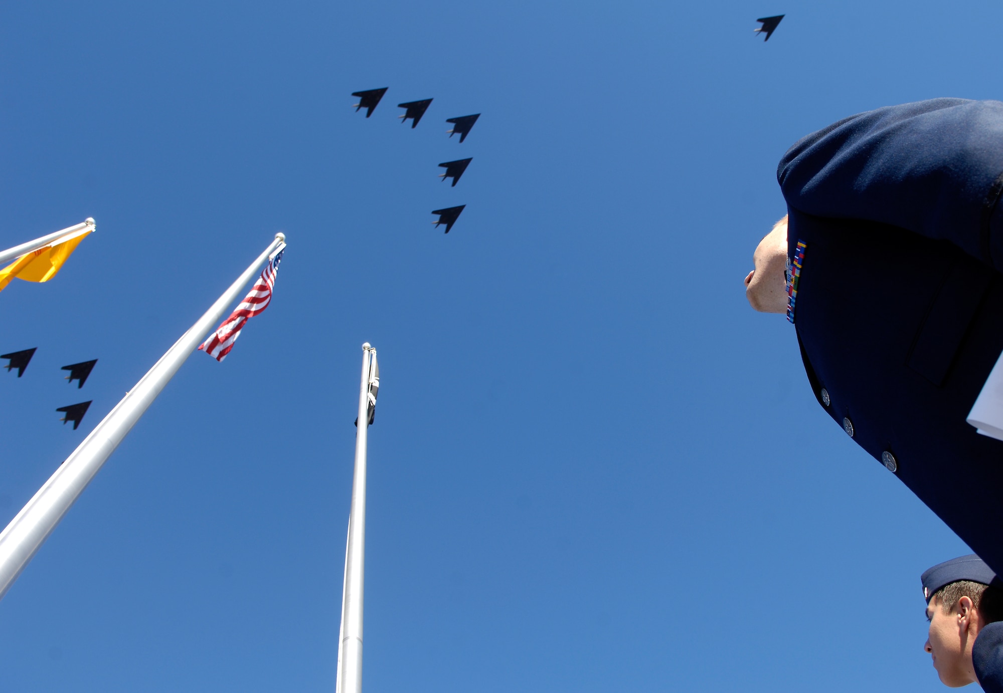 Capt. Heath Armstrong (front) and 2nd Lt. Scott Panzer watch as a formation of F-117 Nighthawks pass overhead. The formation was part of the Nighthawk's 25th anniversary and 250,000 flying-hour celebration at Holloman Air Force Base, N.M.  The formation consisted of 25 planes staggered into five separate groups. Captain Armstrong and Lieutenant Panzer are part of the 49th Operations Support Squadron. 
(U.S. Air Force photo/Senior Airman Brian Ferguson)
