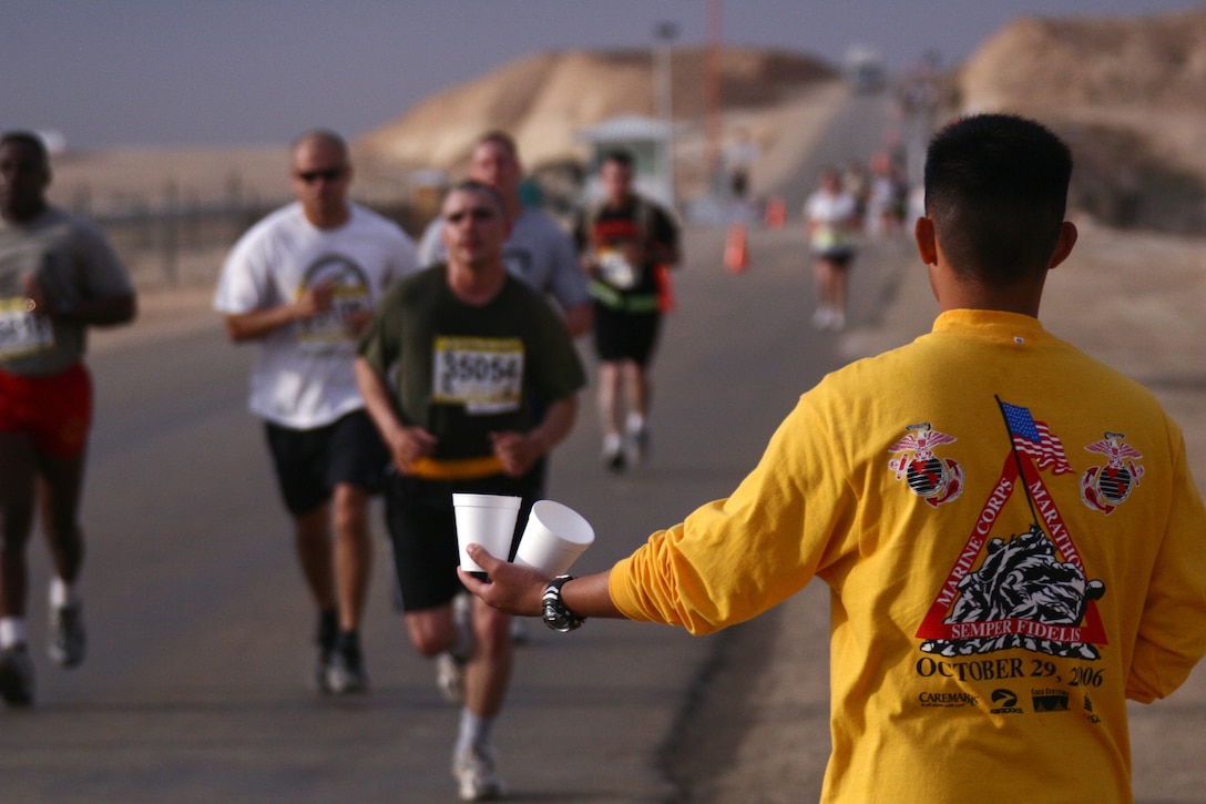 A volunteer service member hands out water to runners of the first satellite Marine Corps Marathon hosted at Al Asad, Iraq, Oct. 29. The runners traveled from all across Iraq to participate in the event and will be added to the books as officially completing the stateside event.