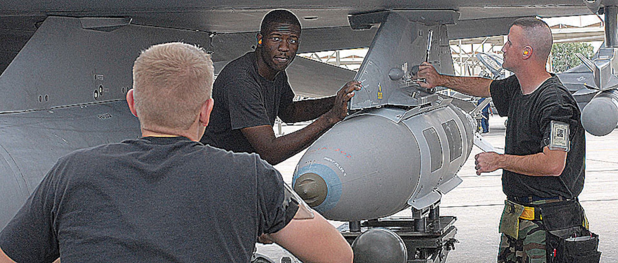 From left:  Senior Airman Simpson Hill, Airman 1st Class Benny Gordon and Staff Sgt. James Tankersley, weapons loaders from the 56th Aircraft Maintenance Squadron, load a Joint Defense Area Munition onto an F-16 Tuesday.