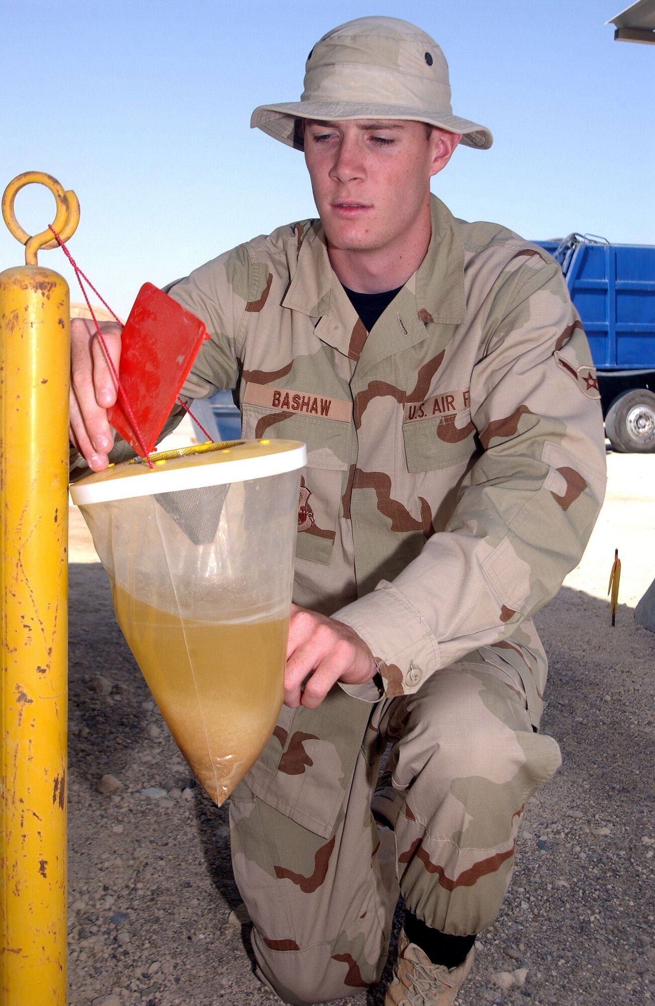 Airman Mark Bashaw, 380th Expeditionary Civil Engineer Squadron entomolgy flight, checks a "barf bag" for flies.  The "barf bag" is a plastic bag filled with protein that attracts flies. (U.S. Air Force photo/Master Sgt. Jason Tudor)