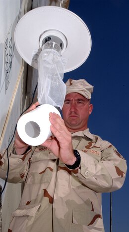 Staff Sgt. Robbie Crumpton, 380th Expeditionary Civil Engineer Squadron, examines a "light trap" for bugs.  The light trap allows Sergeant Crumpton, who works in the entomology flight, and the public health flight to see what sorts of bugs are in season and the potential for diseases like malaria and more.  (U.S. Air Force photo/Master Sgt. Jason Tudor)