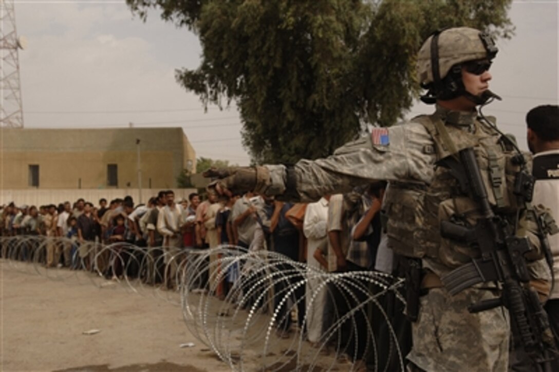 A U.S. Army soldier provides security for a long line of Iraqis waiting for food distribution during a humanitarian mission in the Bayaa district of Baghdad, Iraq, on Oct. 19, 2006.  Soldiers from Alpha Company, 4th Battalion, 23rd Infantry Regiment, 172nd Stryker Brigade Combat Team are providing a safe area for the Iraqis during the distribution.  