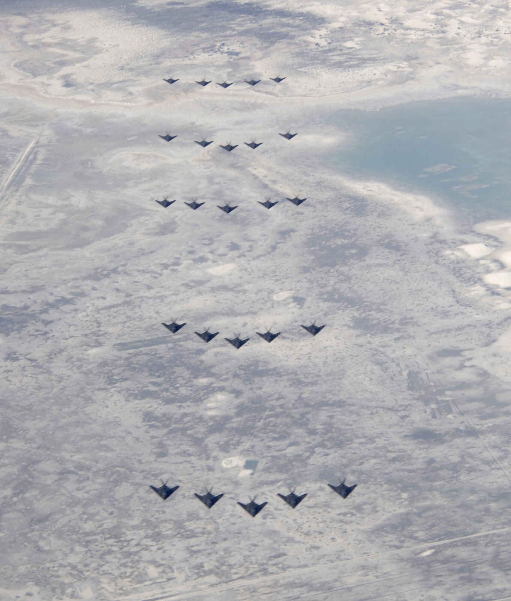 Flying over White Sands and Lake Lucero, 25 F-117A head toward Heritage Park as part of the Silver Stealth celebration Oct. 27, 2006. 