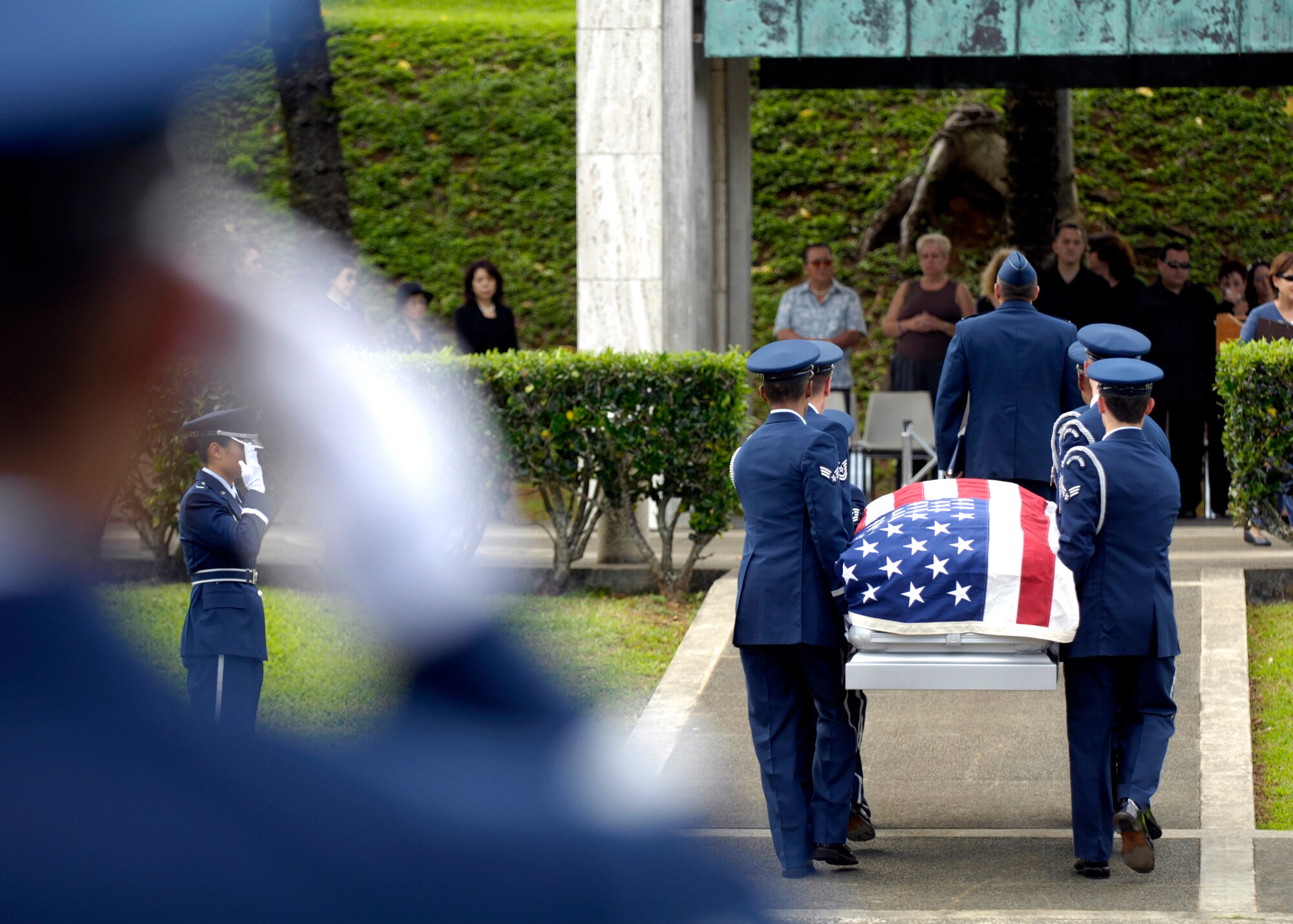 Members of the 15th Airlift Wing Honor Guard at Hickam Air Force Base, Hawaii, salute while others perform pallbearer duties Oct. 26 during a veteran's funeral at Hawaii Veterans Cemetery. The base honor guard is rendering military honors to the veteran and his family. (U.S. Air Force photo/ Tech. Sgt. Shane A. Cuomo)