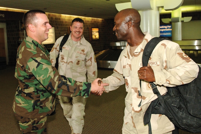 Capt. Dana Metzger, 437th Security Forces Squadron operations officer, welcomes home Tech. Sgt. Jerome Mack and Master Sgt. Donald Hart at Charleston International Airport Tuesday. The sergeants returned from a six-month deployment to Camp Bucca, Iraq, where they assisted with detainee operations.  (U.S. Air Force photo by James Bowman) 