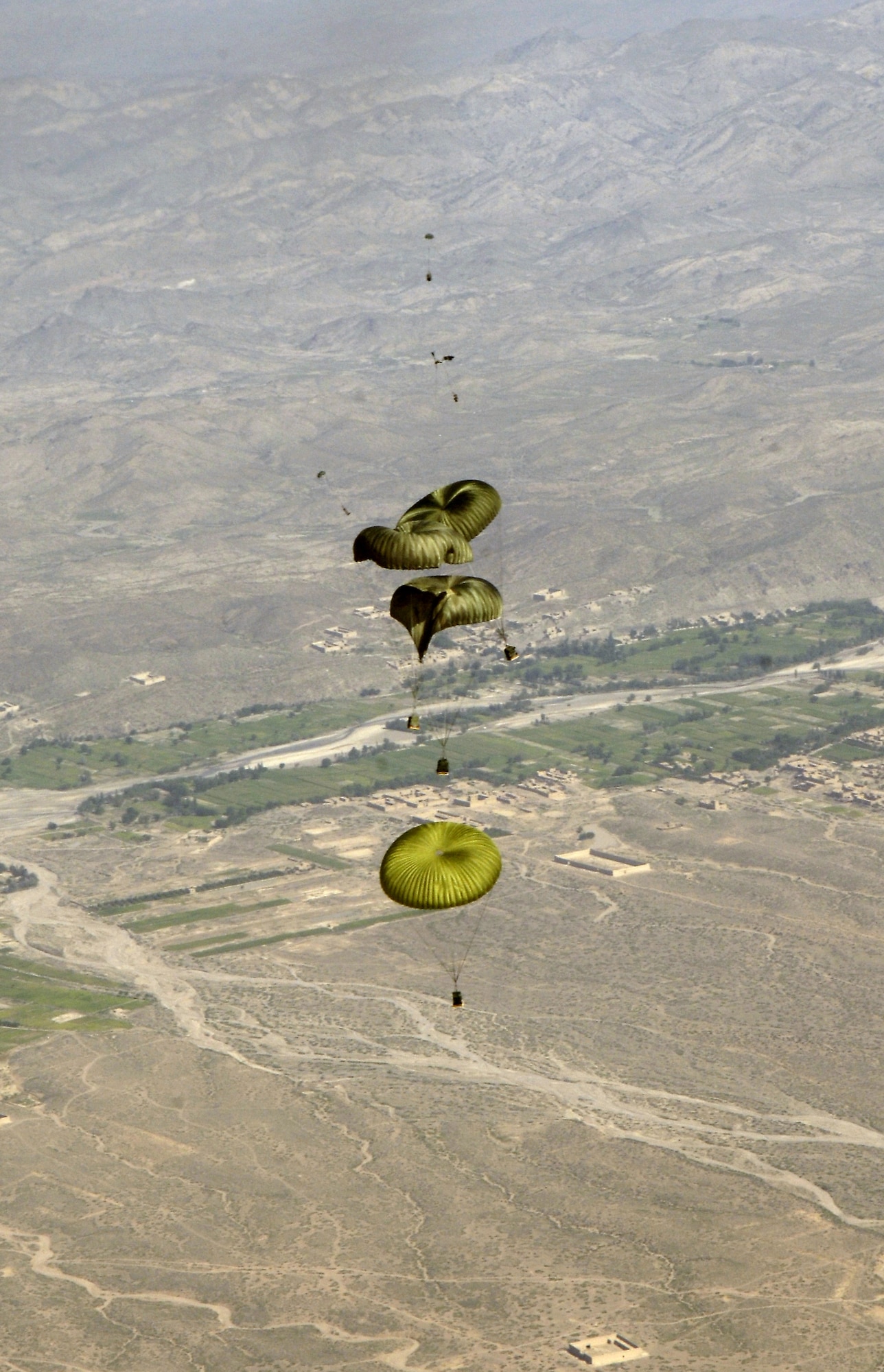 Joint Precision Air Drop System bundles float to the ground after being dropped from a C-130 Hercules Aug. 26. The drop was made from almost 10,000 feet above sea level and was calculated using up-to-the-minute wind data relayed from two small dropsondes deployed 20 minutes earlier. The dropsondes calculate wind speed and relay the information back to the aircraft, helping to calculate the correct drop point. (U.S. Air Force photo/Senior Airman Brian Ferguson) 