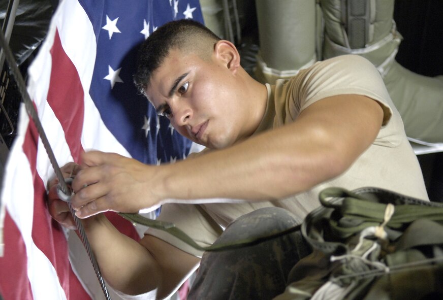 Army Spc. Oscar Osorio attaches the parachute activation cord of a Joint Precision Air Drop System bundle to a C-130 Hercules static line before an airdrop over Afghanistan Aug. 31. Specialist Copley is a parachute rigger with the 647th Quartermaster Detachment. (U.S. Air Force photo/Senior Airman Brian Ferguson)
